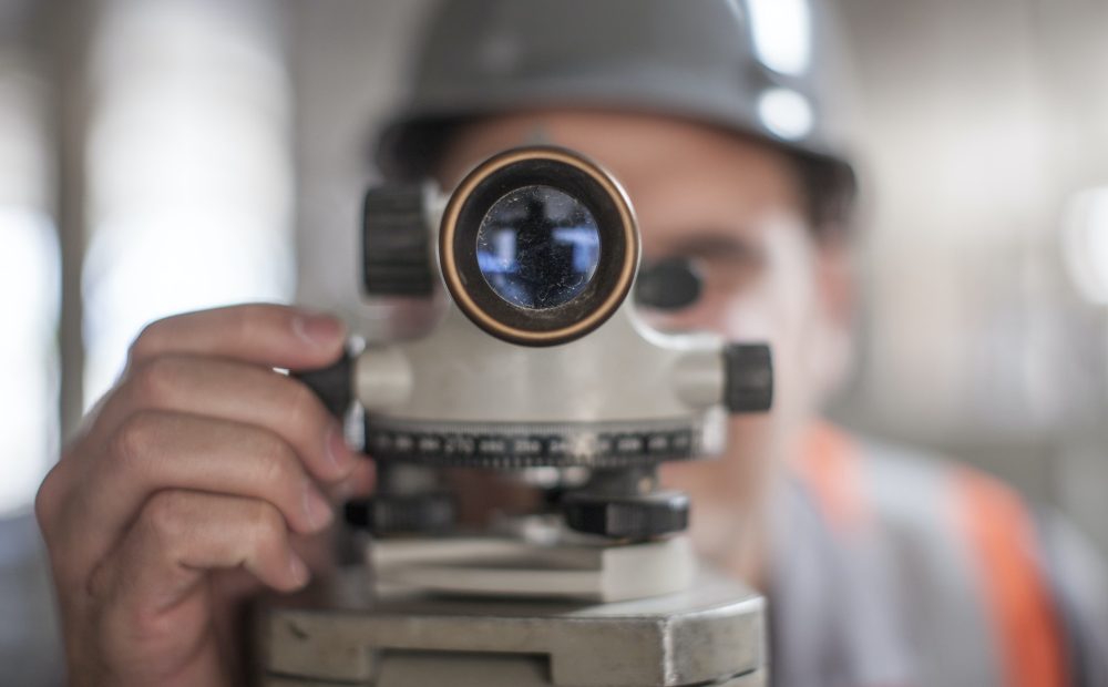 close-up-of-young-male-surveyor-looking-through-theodolite-on-construction-site.jpg